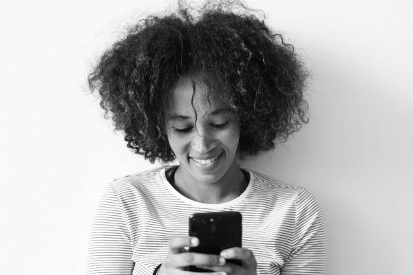 black and white photo of woman smiling at phone